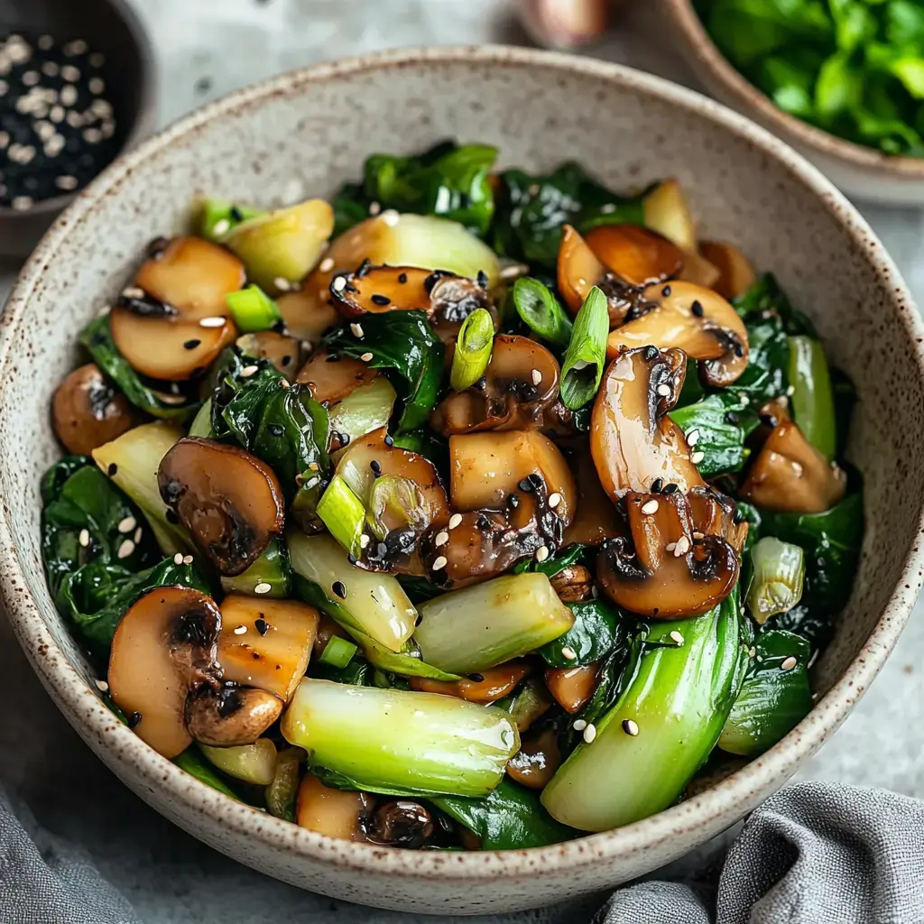 A bowl of stir-fried mushrooms and leafy greens, garnished with green onions and sesame seeds.