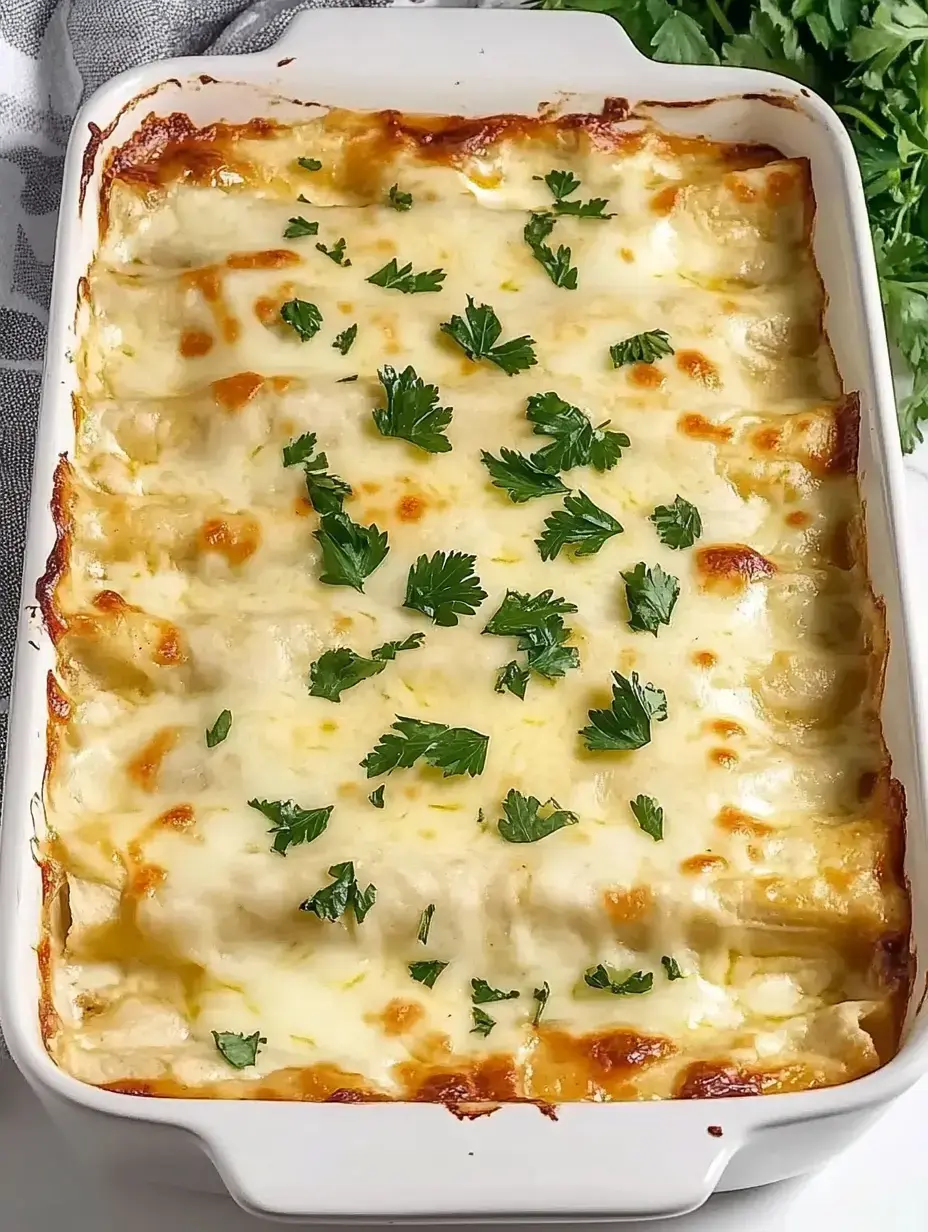 A baked dish of creamy enchiladas topped with melted cheese and garnished with fresh parsley.