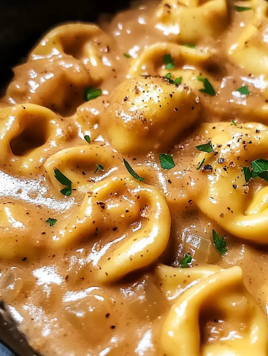 A close-up image of creamy pasta with a rich sauce, garnished with fresh herbs.