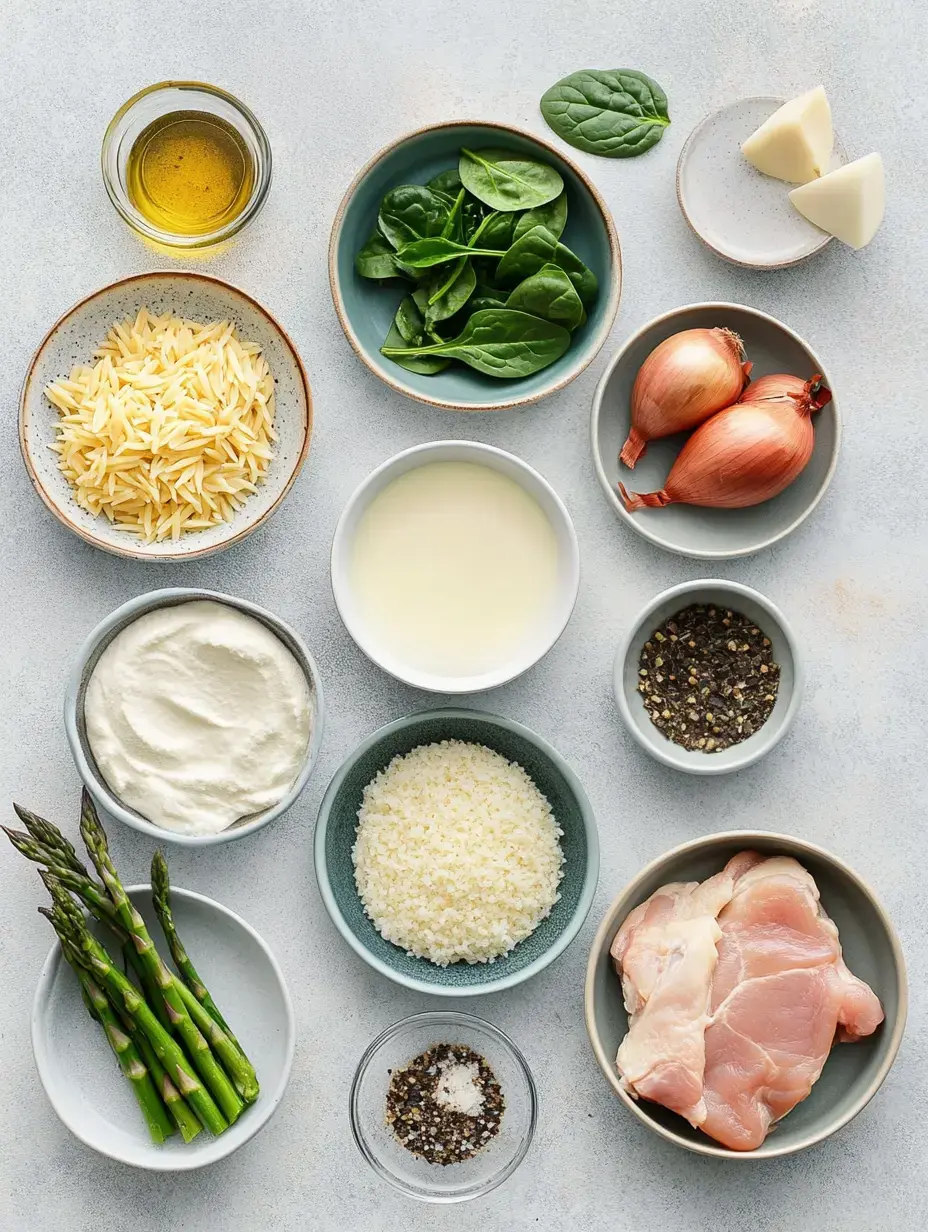 An assortment of ingredients including orzo pasta, chicken, spinach, shallots, asparagus, cream, Parmesan cheese, olive oil, and various seasonings arranged in bowls on a light background.