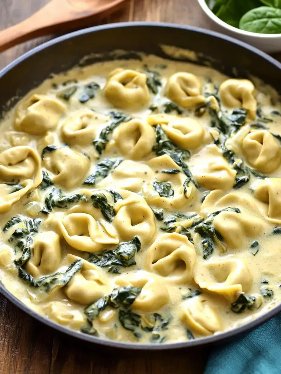 A skillet filled with creamy spinach and tortellini pasta, cooked in a rich sauce.