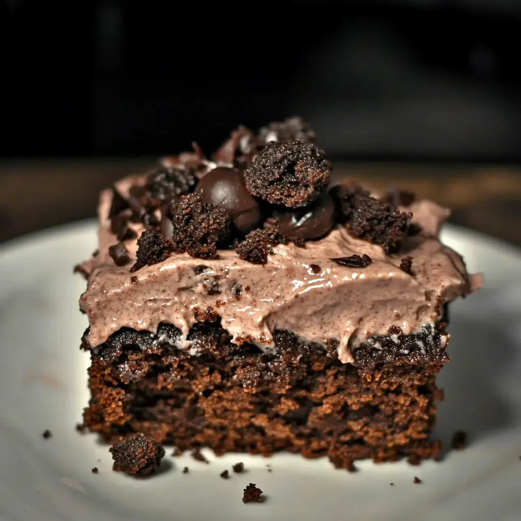 A slice of chocolate cake topped with creamy frosting and crushed chocolate cookies.