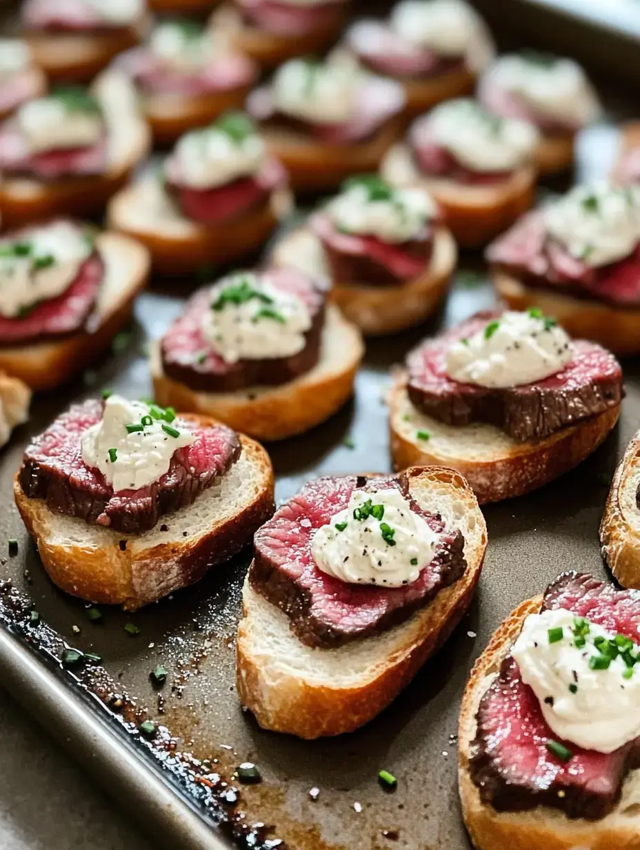 A tray of sliced bread topped with pieces of steak and dollops of creamy sauce, garnished with chopped chives.