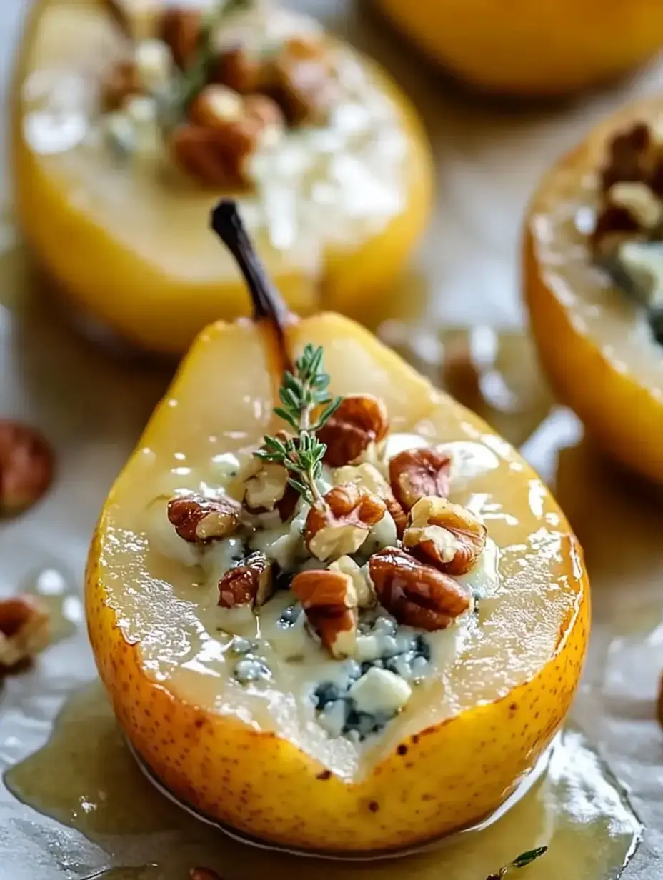 A close-up of halved baked pears topped with blue cheese, walnuts, and a sprig of thyme, drizzled with honey.