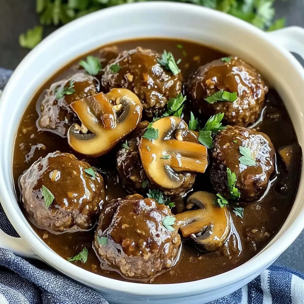 A bowl of meatballs with mushrooms and herbs.
