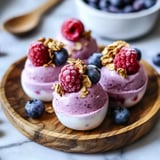 Three desserts with berries and granola on top.