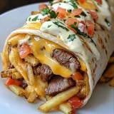 A burrito with meat and cheese on top.